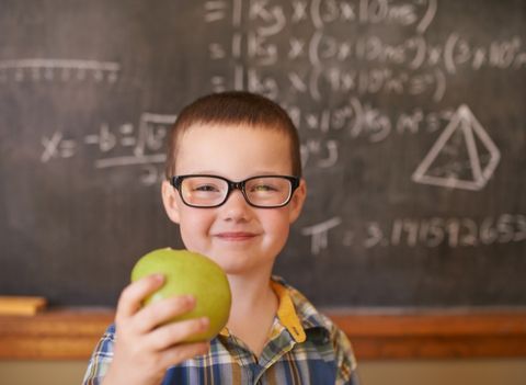 egészséges kisfiú iskolában tábla előtt almával a kezében