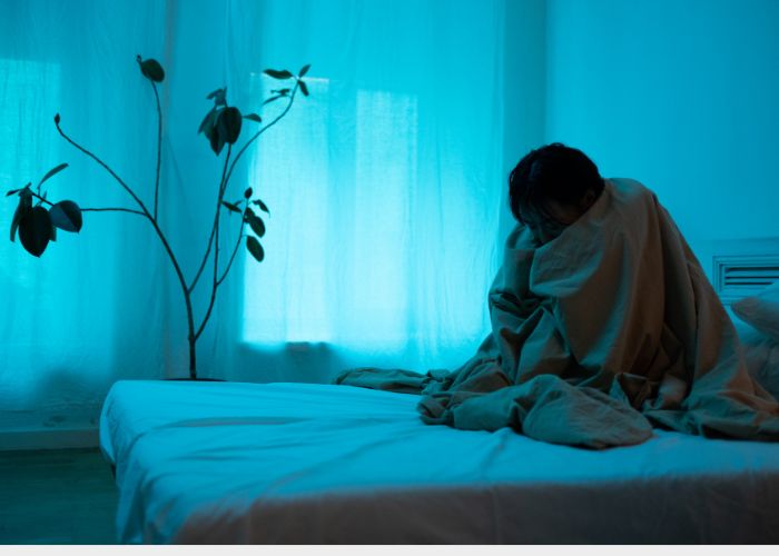 depressziós nő a takaróba burkolózva sötét szobában