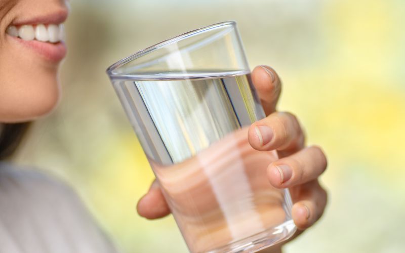 egy pohár vizet tartó női kéz