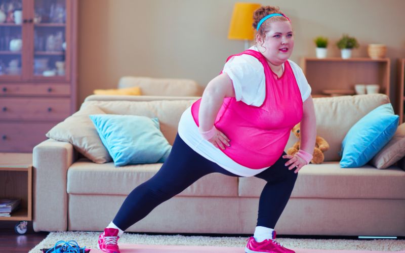 túlsúlyos nő tornázik a szobában