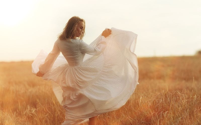 táncoló nő fehér ruhában egy réten